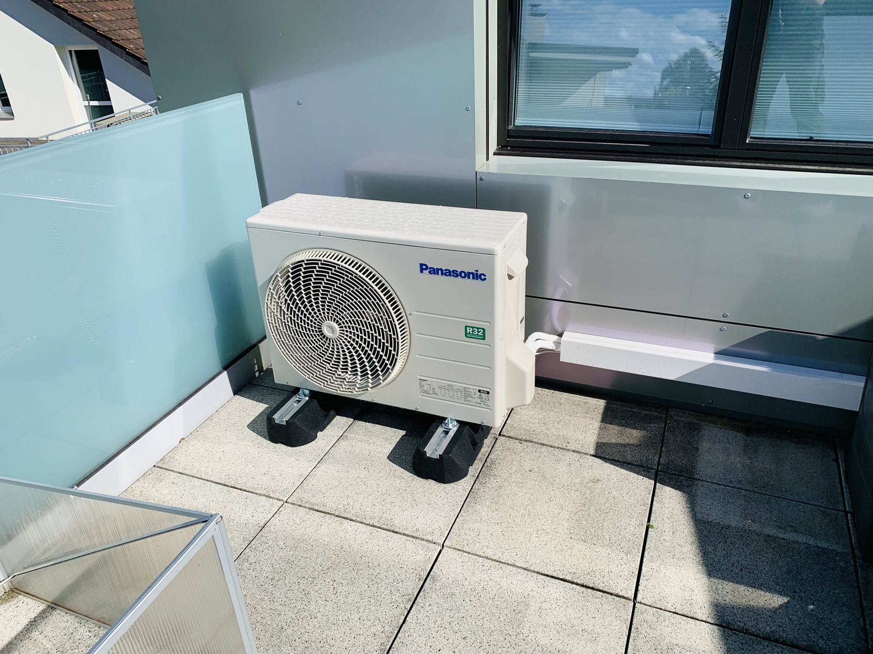 Panasonic-Aussengerät auf einer Terrasse mit Glasbrüstung
